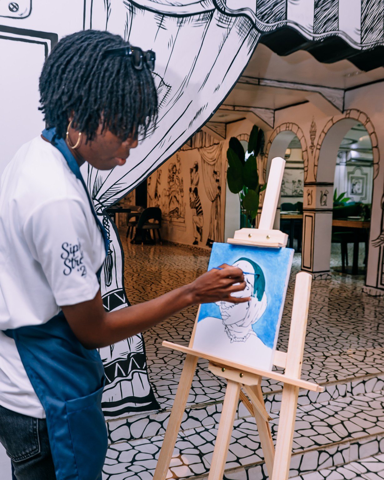A guest painting at an easel inside Sketch